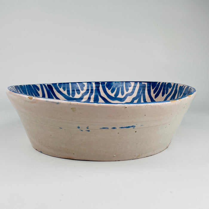 Angled overhead view of large antique Spanish lebrillo with cobalt blue heraldic falcon and stylised scrollwork, demonstrating Andalusian craftsmanship ideal for Mediterranean decor, rustic kitchens, cottage decor, Japandi accents and curated ceramic wall art.