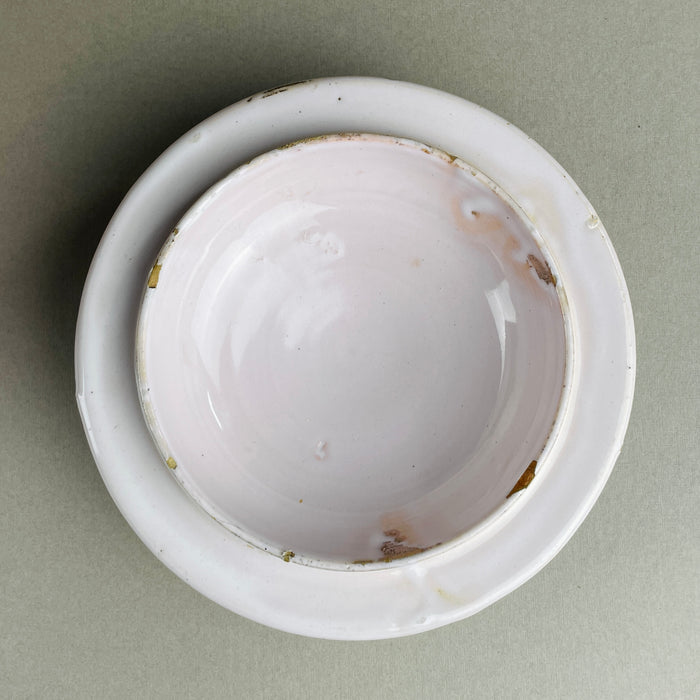 Angled close-up of antique French confit pot with lid, stoneware pottery from Martres Tolosane. White glaze with subtle imperfections highlights age. This traditional pot à conserve storage jar can also serve as a rustic urn in farmhouse or wabi-sabi interiors.