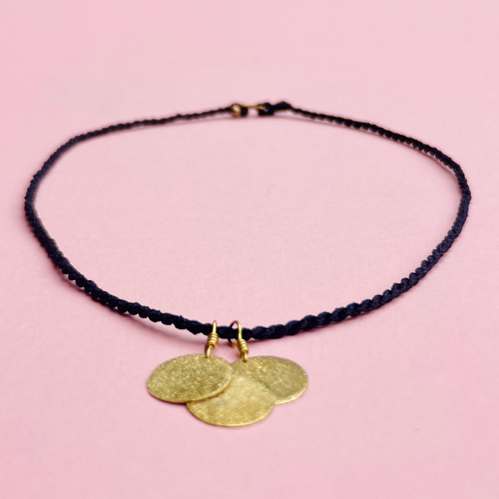 Necklace styled alongside natural textures (linen, figs) to reflect Mediterranean boho inspiration. Keywords: rustic coin pendant, festival necklace, artisan design, summer accessory.