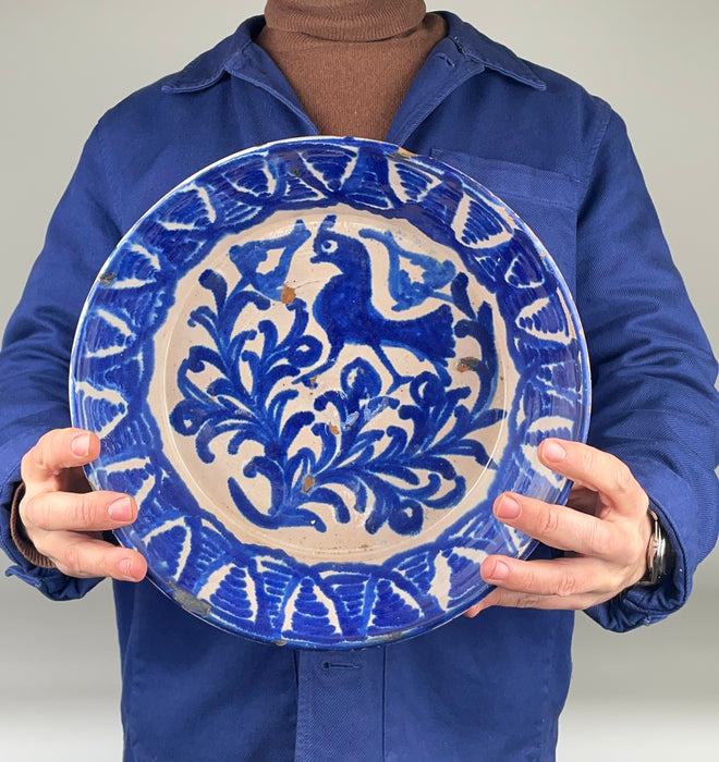 Full frontal view of a 19th-century Fajalauza ceramic wall bowl with pierced hanging holes, allowing use as wall hanging ceramic decor or display on a shelf or table. The bold cobalt brushwork and folk bird motif make it suitable for Mediterranean Decor, Coastal Decor, and Cottage Decor, while the handmade irregularities align with Wabi Sabi decor aesthetics.