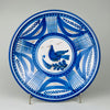 Antique Spanish majolica wall plate from early 20th century Talavera de la Reina, formed as a shallow tin glazed earthenware charger and hand painted in cobalt blue with manganese brown accents. A stylized bird stands on a leafy branch within concentric bands of foliate arcs, lattice panels, dots, and linear ornament, creating strong Mediterranean decor.