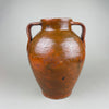 Antique terracotta pot with twin handles, warm red clay body, and a glossy brown slip glaze that pools around the shoulder and neck. The ovoid form and wide mouth read as a decorative vase for vintage home decor, styled as farmhouse decor or French country decor with wood, linen, and natural tones.
