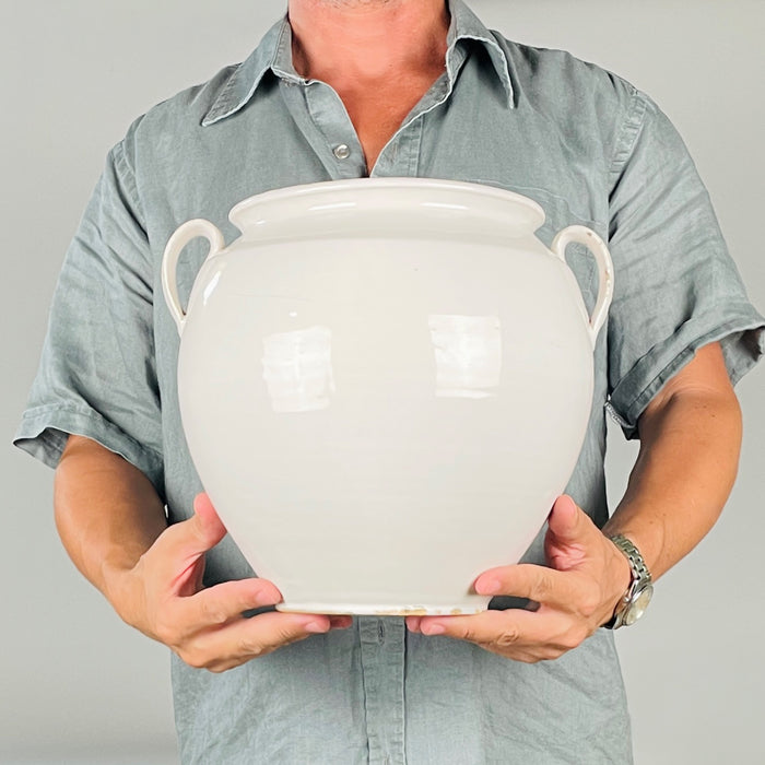 Large Martres Tolosane ceramic jar with a fully glazed pale interior, wide circular opening and softly rounded rolled rim. This early 20th century French faience confit pot was traditionally used to preserve food in fat; its clean open form now lends itself to dried branches, utensils or a tabletop arrangement.
