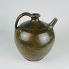 A nineteenth century French terracotta vase with a full rounded body, short flared neck, broad loop handle and separate upward spout. Its glossy green glaze varies through olive and brown, with scattered chips and worn patches revealing the clay beneath. The substantial pottery jug form makes an expressive decorative piece for French country decor.