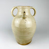 Antique French cruche pot displaying the applied pouring spout, twin loop handles and broad neck that distinguish this regional household vessel. An old hairline follows part of the spout attachment with localized glaze loss, while the surrounding cream terracotta surface retains natural throwing marks and patina.