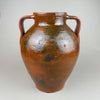 Detail of the left handle and shoulder on an antique terracotta pot, showing the thick hand-formed handle join, glaze pooling at the attachment point, and the subtle surface pitting typical of kiln-fired clay. This decorative pottery vessel suits wabi sabi spaces and layered rustic home decor with collected ceramics.