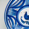 Broad decorative border on the antique Spanish charger combines sweeping cobalt leaves, small blue botanical sprigs, striped lattice sections, dotted rings, and delicate brown wave motifs. These rhythmic hand painted elements surround the central bird and give the Talavera majolica plate the graphic presence associated with collectible European country decor.