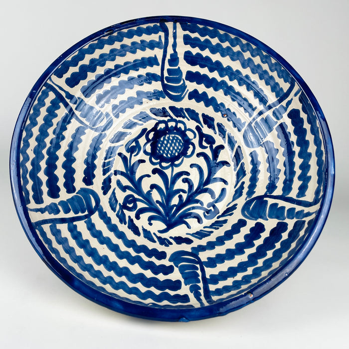 Large Spanish Fajalauza lebrillo bowl in hand painted blue and white earthenware, displayed as a decorative centerpiece with oranges. This Granada pottery bowl has a wide round form, floral center, and radiating wave motifs typical of traditional Fajalauza ceramics. Its scale makes it ideal for Mediterranean decor, Spanish decor, vintage home decor, or a statement fruit bowl on a dining table.