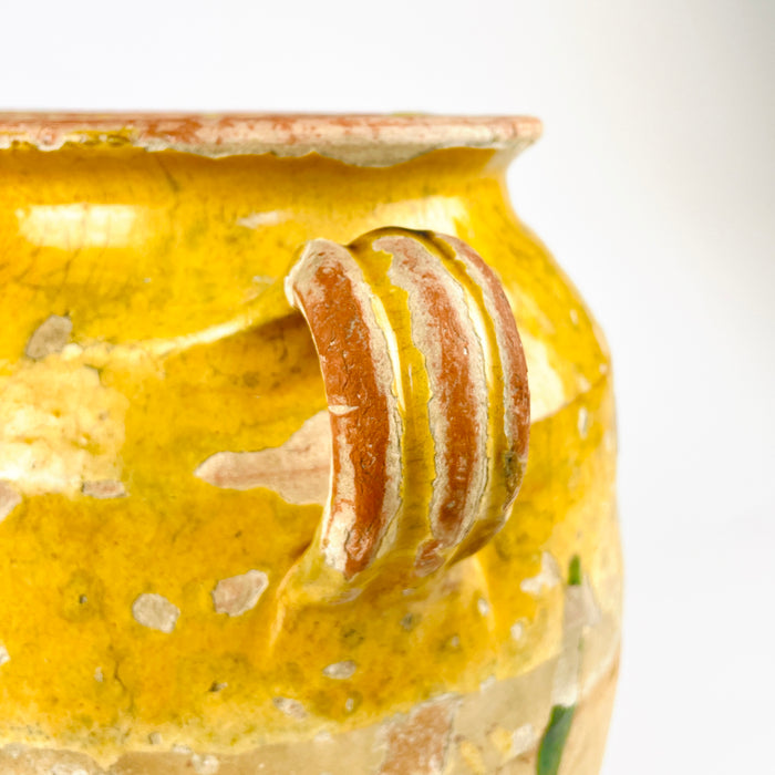 Yellow glazed French confit pot in antique terracotta, showing the thick glaze concentrated around the shoulder and interior and the exposed clay body below. The crackle pattern, glaze flaking, and worn surface reflect age and traditional use. This French pottery jar has the understated texture collectors seek for wabi sabi decor, farmhouse decor, and old-world kitchen styling.