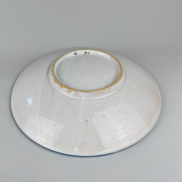 Antique blue bird plate from Talavera de la Reina, Toledo, made in tin glazed earthenware with a gently raised rim and deep footed profile. Repeated dots, stripes, curved leaves, and small botanical marks create movement around the central bird without obscuring it, making the charger distinctive traditional home decor.
