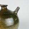 The broad handle of a French green glazed terracotta vase has a central lengthwise groove and joins the rounded body below the shoulder. A zigzag band continues across the glazed surface beside it, while small orange patches mark areas of glaze loss. The handmade pottery jug form brings texture and character to cottage decor or country interiors.