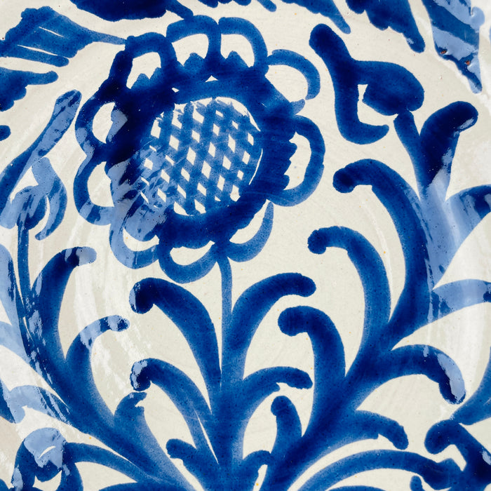 The deep basin and raised foot of this large Granada Fajalauza lebrillo demonstrate the strength of its traditional earthenware form. Loose cobalt blue brush motifs decorate the creamy exterior, while the hand painted sunflower and wave bands continue across the interior. The bowl is suitable for Spanish decor, French country decor, cottage decor, farmhouse decor, or use as a striking ceramic centerpiece.