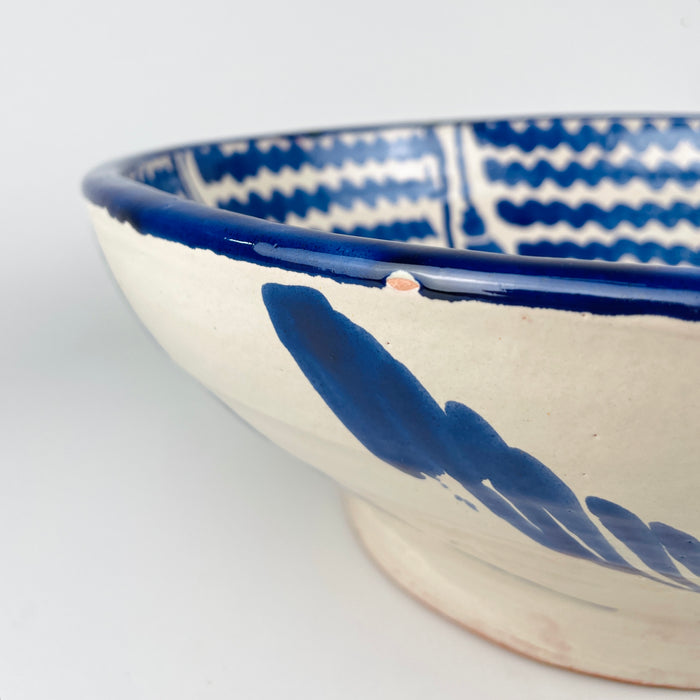 Close detail of the central flower motif inside a vintage Fajalauza bowl from Granada, Spain. The design is painted in cobalt and lighter blue tones over a tin glazed earthenware surface, with visible handmade variation and artisan brushwork. This Spanish pottery bowl adds texture and color to wabi sabi decor, japandi decor, Mediterranean decor, or a layered vintage kitchen display.