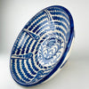 Large Spanish decorative bowl in the Fajalauza tradition, formed from terracotta earthenware and finished with white glaze and cobalt blue hand painting. The broad lebrillo shape frames a sunflower motif, layered foliage, and repeated wavy bands, producing a bold graphic surface. Its generous scale makes it suited to Mediterranean decor, rustic home decor, cottage decor, and a blue and white ceramic collection.