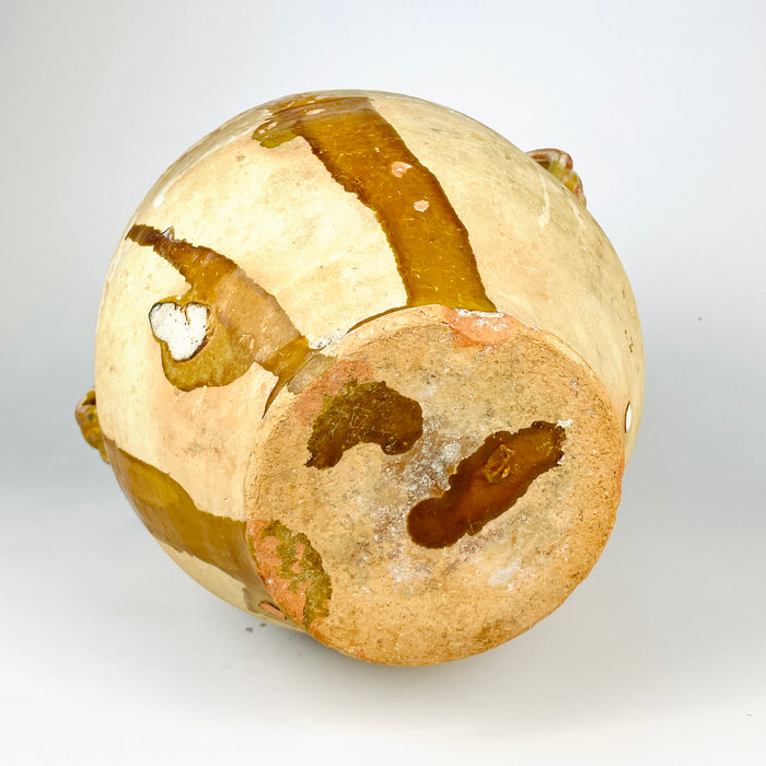 Antique French pottery jar with confit pot form and yellow glaze, showing the tactile beauty of old earthenware made for everyday household use. The vessel has visible craquelure, glaze losses, and a worn rim, all consistent with authentic age. This farmhouse decor piece also suits French country decor and rustic home styling as a terracotta jar or decorative vase.