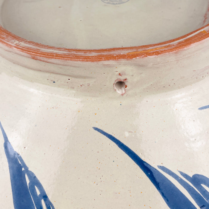 The pierced base of this Granada lebrillo bowl is designed for wall display, allowing the large hand painted ceramic to function as decorative wall art as well as a tabletop bowl. Glazed terracotta, cobalt blue exterior brushwork, and the raised foot remain clearly visible. This practical hanging feature adds versatility for Spanish decor, Mediterranean decor, farmhouse decor, or a curated pottery wall.