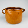 Upper body and second loop handle of the signed Vallauris cooking pot, showing the dark rim glaze, honey mustard earthenware surface and natural glaze variation from historic use. The substantial two-handled form identifies this as an antique French marmite crock with lid and distinctive Provence pottery character.