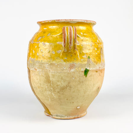 Large antique French confit jar in earthenware with yellow glaze and classic rural pottery form. This 19th century French pottery vessel has two loop handles, a rolled lip, and a hand-thrown body with strong surface patina. The crackled glaze, worn edges, and exposed clay create a decorative terracotta jar that works beautifully in French country decor and wabi sabi decor.