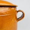 Closed antique Vallauris marmite with domed lid, small circular knob, twin loop handles and a high rounded body in mustard glazed earthenware. The Foucard Jourdan maker and traditional form give this French pottery crock strong historical character for cottage decor, collected French cookware or a console display.