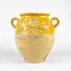 Antique French confit pot in yellow glazed terracotta, a large 19th century pottery jar with rounded body, flared rim, and small applied loop handle. The upper section carries warm ochre glaze with visible craquelure and glaze loss, while the lower body remains unglazed and pale. This French country pottery piece suits farmhouse decor, Mediterranean decor, and rustic home decor.