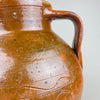 Top view into a large terracotta pot with twin handles, showing the thick rounded rim, interior wear, and the contrast between glossy brown glaze and exposed clay at the lip. This antique decorative pottery piece reads well in wabi sabi and Japandi rooms where texture and patina are key.