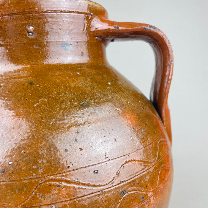 Top view into a large terracotta pot with twin handles, showing the thick rounded rim, interior wear, and the contrast between glossy brown glaze and exposed clay at the lip. This antique decorative pottery piece reads well in wabi sabi and Japandi rooms where texture and patina are key.