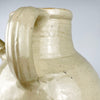 Large antique French pottery vessel with a wide mouth and glazed interior, made for the traditional cruche form and now intended as decorative display. The rolled rim shows rubbing and small nicks consistent with age, while the ivory glaze and substantial twin handles create a distinctive neutral ceramic accent.