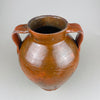 Full view of a large antique terracotta pot with two loop handles and a glossy brown slip glaze over red clay. The rounded shoulder and tapered lower body give it strong sculptural presence as vintage home decor, suitable as a decorative vase in French country decor or Mediterranean decor.