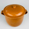 Broad fitted lid and dark glazed rim of the large French terracotta cooking pot, showing how the domed cover rests over the deep Foucard Jourdan marmite. The honey ochre glaze, hand-formed knob and light edge wear are characteristic details of this signed Vallauris Provence pottery crock from the early 20th century.