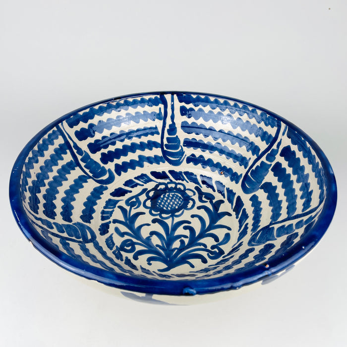 Hand painted Spanish lebrillo bowl in the Fajalauza tradition, made in glazed earthenware with a broad open shape and classic blue and white palette. The bowl combines a floral center with concentric painted bands and works well as a fruit bowl, table centerpiece, or wall display. It suits Spanish decor, farmhouse decor, cottage decor, and vintage kitchen styling.