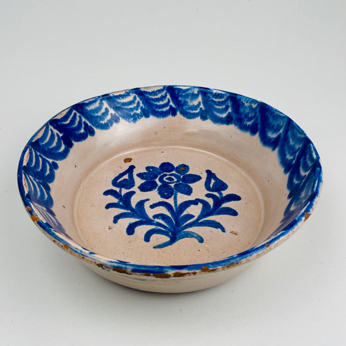 Front view of a 19th century Granada Fajalauza lebrillo, showing hand-painted cobalt blue floral decoration and rhythmic border brushwork on Spanish tin-glazed ceramic. The glaze shows soft cobalt diffusion valued in antique pottery. Suitable as wall hanging ceramic, decorative serving bowl, or table centerpiece for French Country Decor, Cottage Decor, and Farmhouse Decor styling.