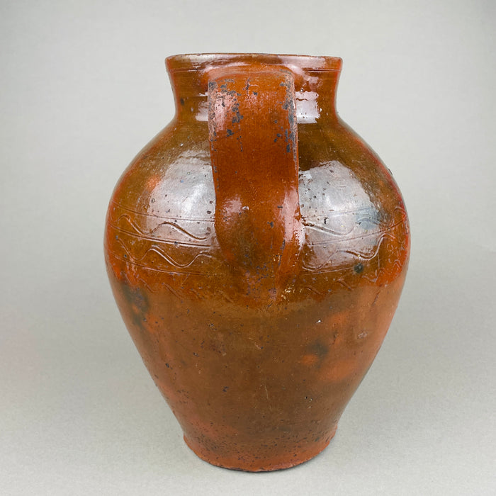 Rear view of the antique terracotta pot, highlighting the twin handles, glaze runs, and subtle color shifts from firing—brown, ochre, and red clay tones. This decorative pottery vessel can anchor a console or open shelf, aligning with rustic home decor, farmhouse decor, and collected ceramic displays.