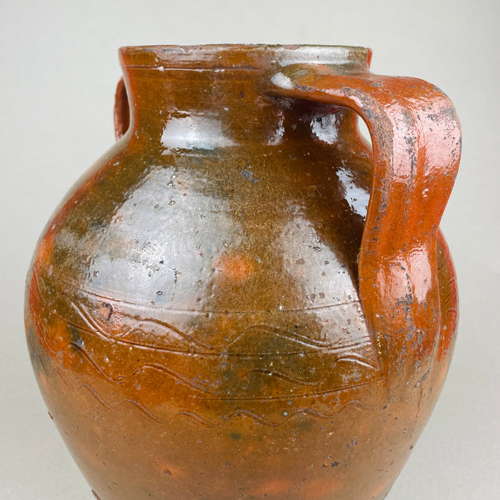 Detail of the right handle and upper body on a large terracotta pot, with semi-gloss brown glaze over red clay and visible firing speckles. The handle’s squared profile emphasizes the utilitarian heritage while presenting as vintage home decor today, ideal for Mediterranean decor shelving or French provincial styling.