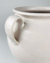 Large antique French white confit pot from Martres Tolosane styled with dried grass stems beside other southern French ceramics. Its creamy glazed faience, broad rounded body, rolled rim and twin handles identify a traditional pot à graisse used for food preservation; today it works as a statement vase within French country decor.