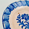 Close-up of the central floral bouquet motif on an antique Spanish lebrillo bowl, revealing layered cobalt brushstrokes, glaze pooling, and soft cobalt bleed into the tin glaze. This Granada pottery piece works as wall hanging ceramic decor or a serving bowl on open shelving, ideal for Wabi Sabi decor and Japandi interiors focused on authentic surface character.