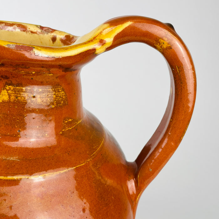 Glazed terracotta gargoulette with a substantial rounded body, short neck and raised pouring spout designed for serving water. This antique French pottery vessel dates to the early 20th century and combines warm honey brown color with yellow accents, making it suitable for rustic home decor and vintage kitchen decor.