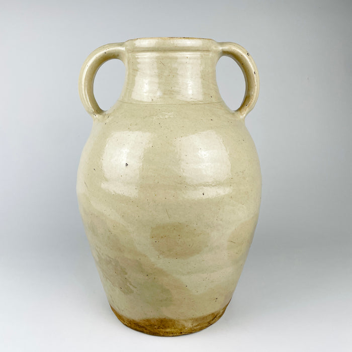 Antique French white cruche with a small impressed numeral on one handle near the rim, preserving evidence of its utilitarian workshop production. The wheel-thrown terracotta body, cream glaze, paired handles and projecting spout combine in a sculptural early 1900s water jug with French provincial character.