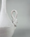 Applied ceramic swan ornament on the vintage Italian vase, showing the bird’s long neck, modeled head, layered wings and lower feather details beneath the glossy ivory white glaze. Small glaze losses, firing marks and darker clay traces remain visible around the relief, documenting the finished surface and age of the sculptural handle.