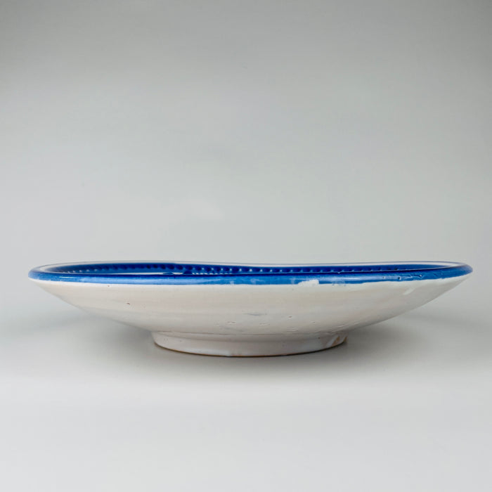 Raised foot ring on the Talavera majolica charger contains two discreet suspension holes for threading hanging wire, confirming its practical use as ceramic wall art. The glazed reverse, exposed clay at the foot, and minor kiln irregularities document the plate’s handmade construction and suit a simple japandi wall art display.