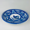 Large Spanish blue bird plate in hand painted Talavera faience, with a white tin glazed ground and a broad cobalt border arranged in alternating leaf shapes, gridded panels, dotted bands, and fine brown scrolls. The shallow charger form and graphic bird motif make this antique pottery a substantial piece of Spanish wall decor.