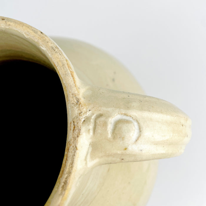 Large French provincial pottery jug with a bulbous shoulder, tall tapering body and warm white glaze over wheel-thrown clay. The restrained palette, handmade asymmetry and timeworn lower edge give the early 1900s decorative vessel a calm sculptural quality compatible with Mediterranean decor and natural materials.