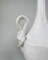 Applied ceramic swan ornament on the vintage Italian vase, showing the bird’s long neck, modeled head, layered wings and lower feather details beneath the glossy ivory white glaze. Small glaze losses, firing marks and darker clay traces remain visible around the relief, documenting the finished surface and age of the sculptural handle.