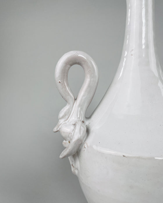 Applied ceramic swan ornament on the vintage Italian vase, showing the bird’s long neck, modeled head, layered wings and lower feather details beneath the glossy ivory white glaze. Small glaze losses, firing marks and darker clay traces remain visible around the relief, documenting the finished surface and age of the sculptural handle.