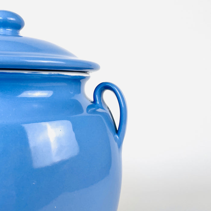 Vintage lidded confit pot from southwest France accompanied by tomatoes and green peppers, recalling its original role in the provincial kitchen. The glazed faience vessel has a rounded body, narrow foot, paired handles and bright blue finish, making it a functional storage jar and a strong French kitchen decor accent.