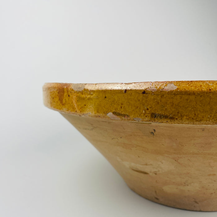 Antique 39cm French terracotta tian bowl in warm golden glaze photographed to reveal surface patina, kiln imperfections, and regional farmhouse character. Ideal for French country dining rooms, Mediterranean rustic kitchens, and organic modern styling where handcrafted pottery adds depth, history, and warm earth tones.