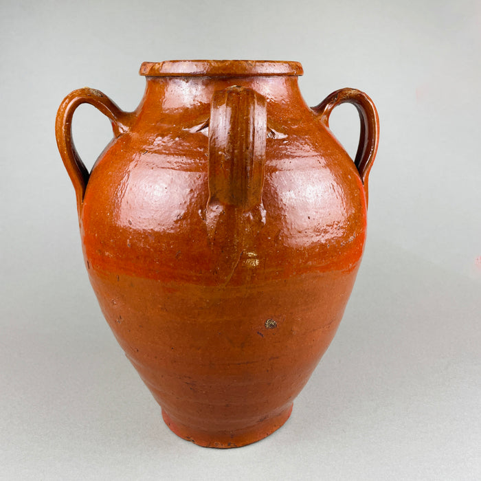 Side profile of a large antique Spanish earthenware jar showing the iron-oxide glaze and balanced proportions. The four-handled orza design and artisanal glaze drips emphasize its handmade construction, suitable for Mediterranean kitchen styling rustic home decor.