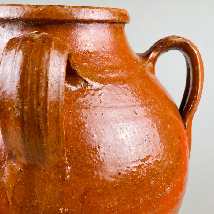 Detailed close-up showing the textured red glaze and curved handle attachments of the antique Spanish orza, capturing the craftsmanship and firing imperfections that authenticate its handmade origin. Ideal for collectors of Mediterranean ceramics and wabi sabi styling.