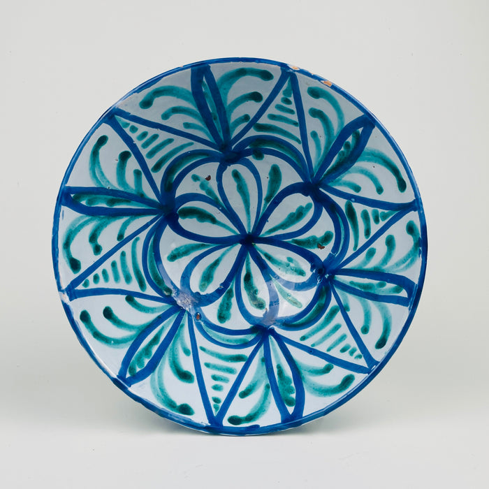 Spanish Granada Fajalauza lebrillo bowl in blue and green on a white tin glaze ground, made in glazed terracotta and sized f     or tabletop use. The deep bowl form supports tapas serving, fruit, or bread, and the pierced hanging holes allow wall hanging ceramic display; condition includes rim glaze losses and edge nicks.