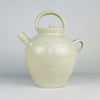 Antique French cruche pot displaying the applied pouring spout, twin loop handles and broad neck that distinguish this regional household vessel. An old hairline follows part of the spout attachment with localized glaze loss, while the surrounding cream terracotta surface retains natural throwing marks and patina.