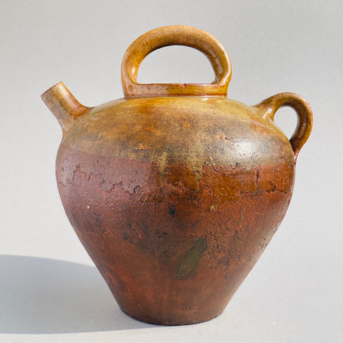Rustic French countryside pottery jug with honey-brown glaze and striking curves, perfect for interior styling.